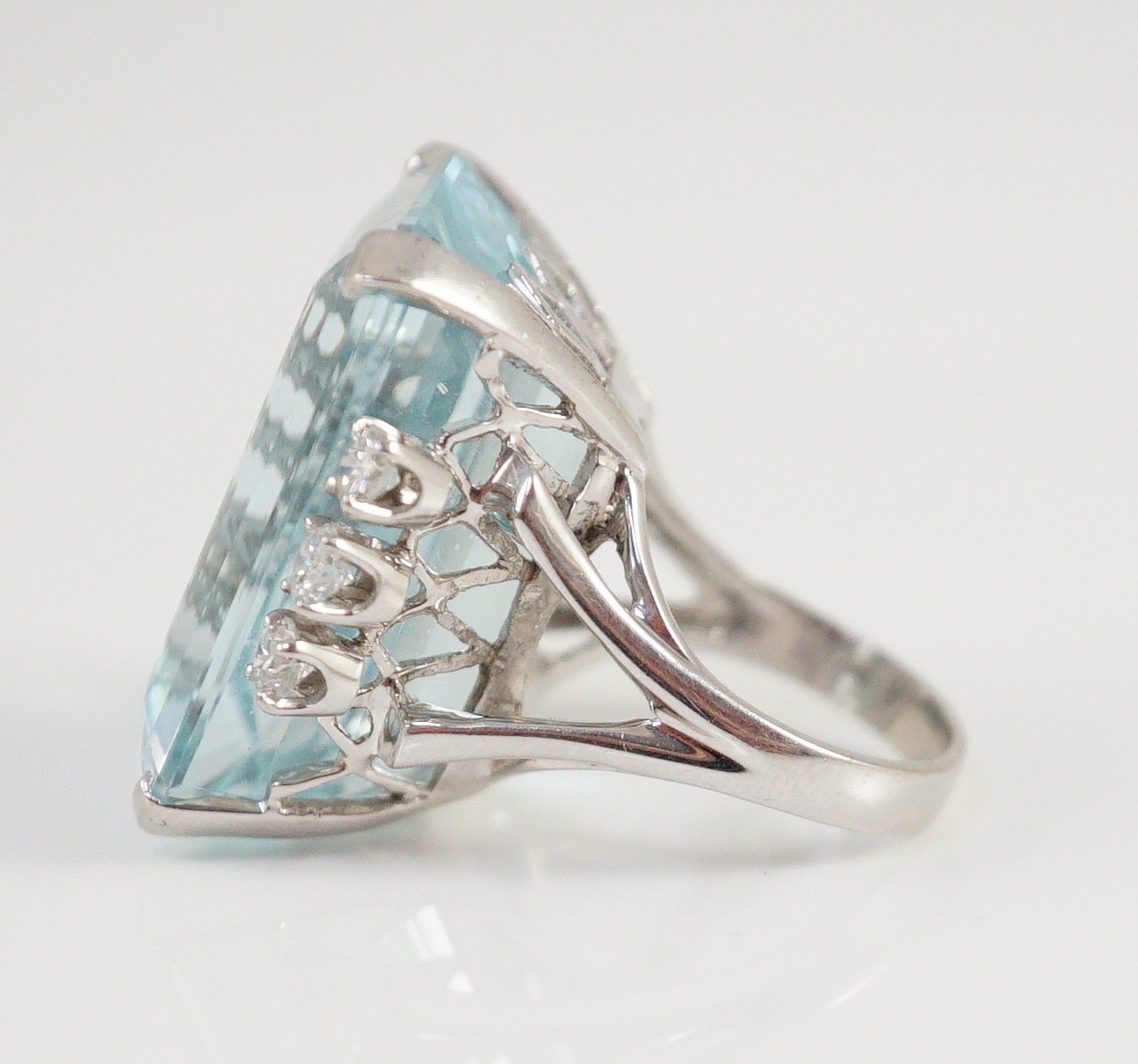 A large modern 14k white gold and emerald cut aquamarine set dress ring, flanked by six round cut diamonds